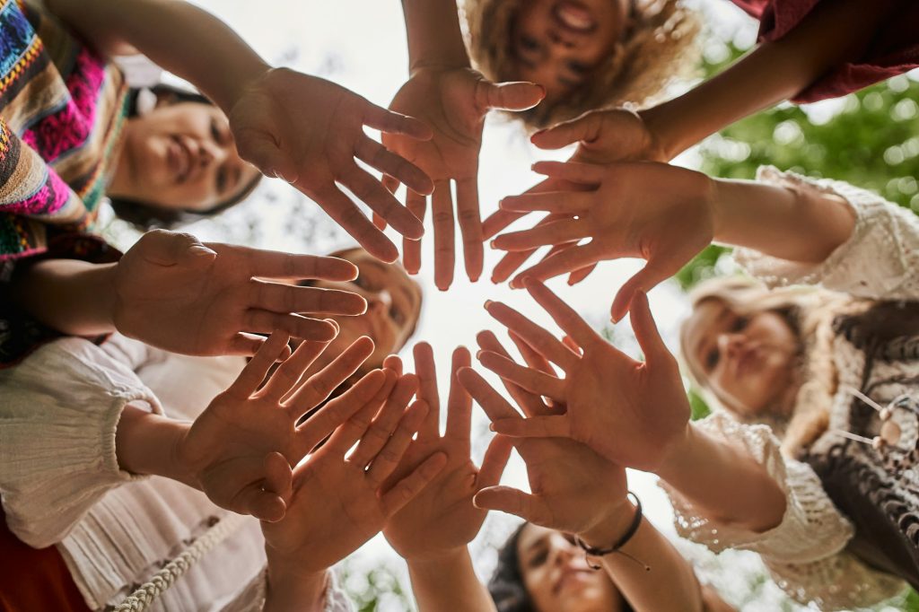 bottom view of blurred interracial women waving hands at camera in retreat center